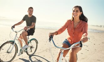 Ein glückliches Paar macht einen Radausflug am Strand und genießt ihre perfekte Sehkraft nach einer Behandlung im sehkraft Augenzentrum