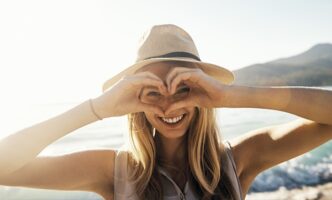 Glückliche Frau nach einer Behandlung im sehkraft Augenzentrum zeigt vor ihren Augen ein Herz.